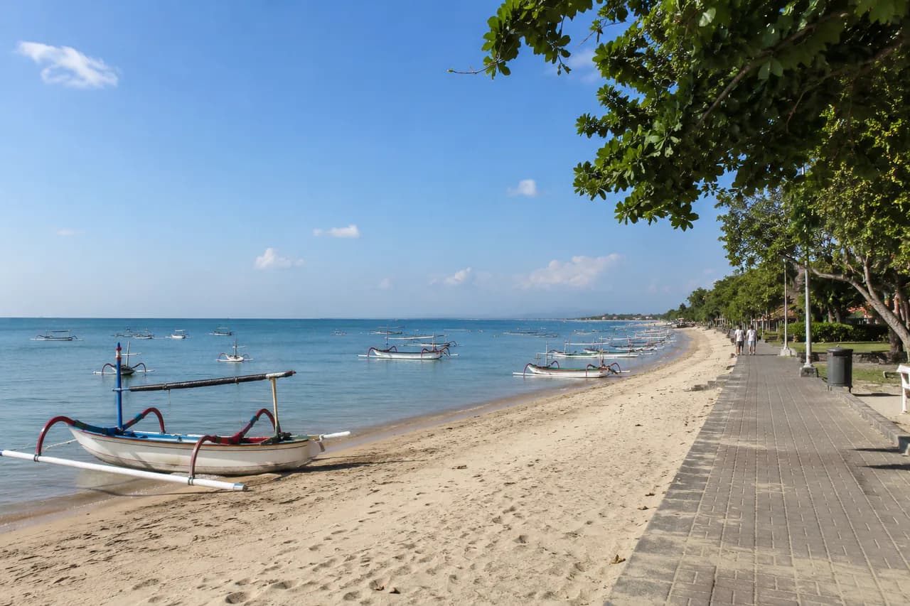 Pantai Sanur dengan perahu tradisional dan jalur pesisir di tepi laut Bali.
